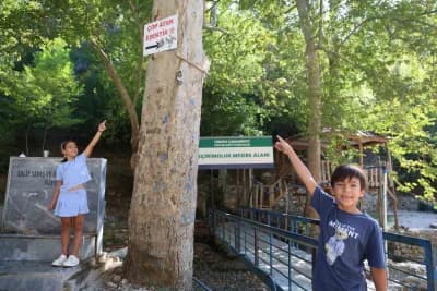 Adana Feke Geçirimoluk Mesire Alanı'nda 'Çöp atan eşektir' yazılı tabela ve çevrede çöplerin toplandığı alan