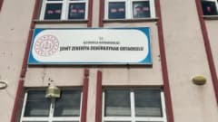 Altınyayla Şehit Zekeriya Demirkaynak Ortaokulu bahçesinde öğrenciler ve yöneticiler çevre temizliği yaparken ve duvarla