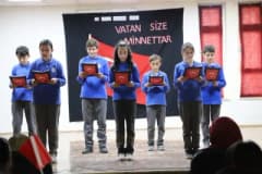 Bayburt Gaziler Ortaokulunda öğrencilerin Gaziler Günü programı sırasında sahnede şiir okuması ve etkinlikler