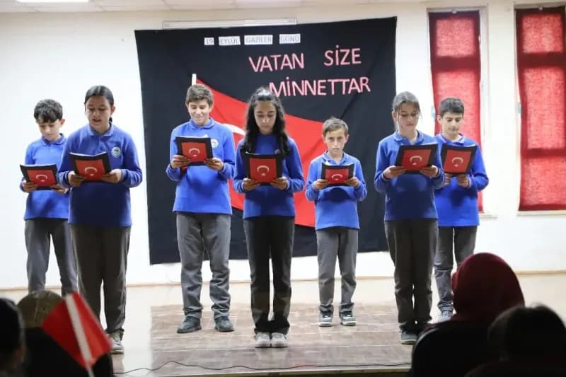 Bayburt Gaziler Ortaokulunda öğrencilerin Gaziler Günü programı sırasında sahnede şiir okuması ve etkinlikler