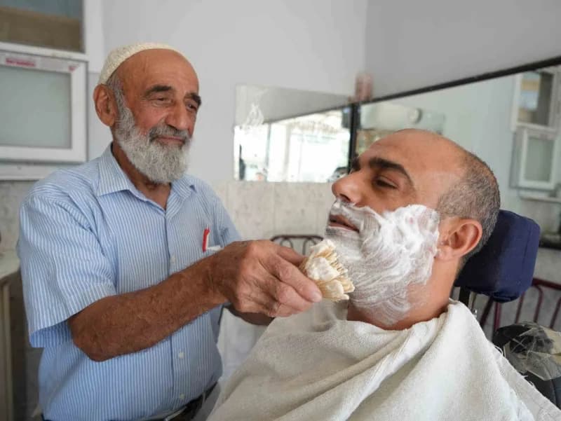 Abdulkadir Aksoy, 65 yıldır berberlik mesleğini sürdürerek müşterilerini tıraş ediyor.