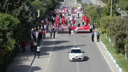 Adıyaman Besni'de 28. Eğitim Bayramı yürüyüşü ve açılış töreninden katılımcılar Türk bayraklarıyla yürürken
