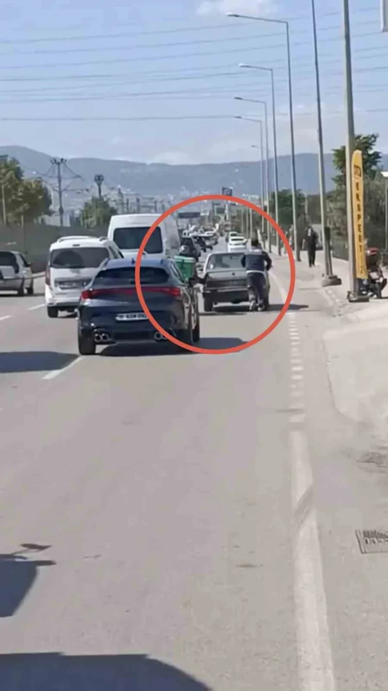 Bursa’da arızalanan otomobili itmek için motosikletinden ayağını uzatan motokurye