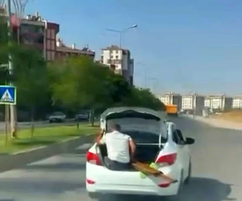 Diyarbakır Yenişehir ilçesinde seyir halindeki otomobilin bagaj kapısında oturan çocuk ve bagajda malzeme taşıyan kişi