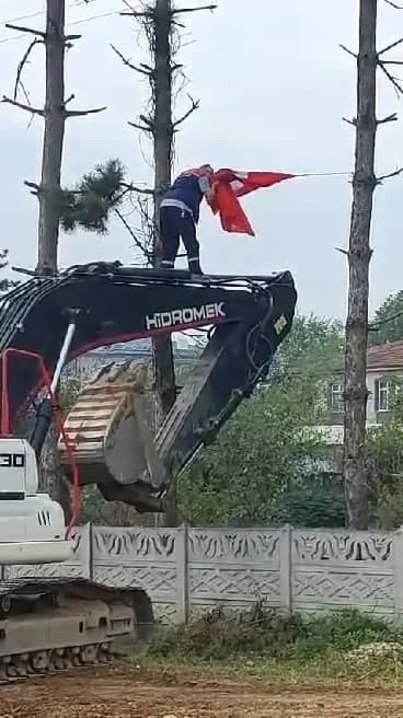 Düzce’de çalışma yaptığı sırada katlanan Türk bayrağı’nı fark ederek iş makinesinin üzerine çıkıp düzelten ekskavatör op