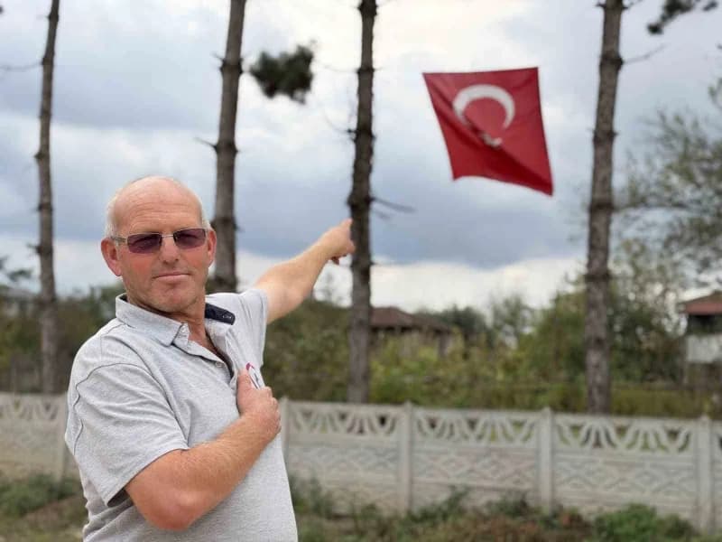 Düzce'de iş makinesi operatörü Mehmet Akçay, iş makinesinin kepçesine çıkarak katlanan Türk bayrağını düzeltiyor