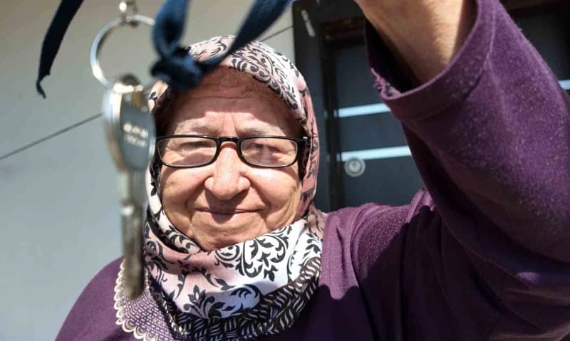 Mersin Erdemli'de gönüllülerin desteğiyle yapılan yeni evinde mutlu olan 69 yaşındaki Fatma Dinç anahtarını gösteriyor