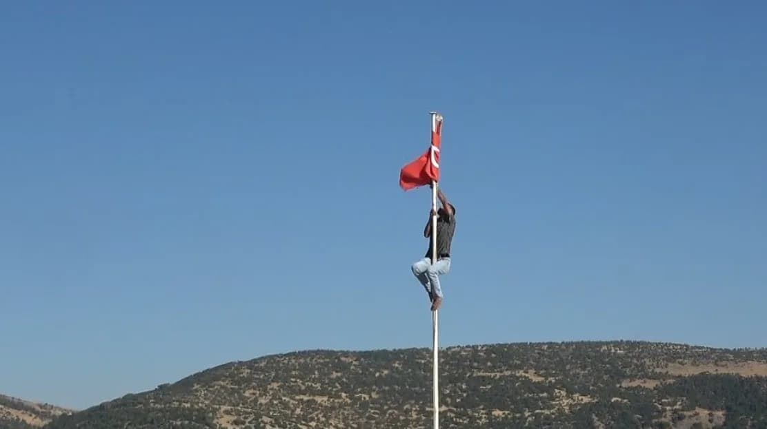 Kilis Polateli'deki Ravanda Kalesi önünde direğe tırmanan genç Türk bayrağını düzeltiyor