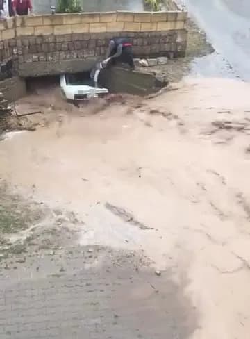 Sel sularının köprü altında sıkıştırdığı araçta bulunan vatandaşlar, çevredekilerin aracın arka camını kırmasıyla kurtar