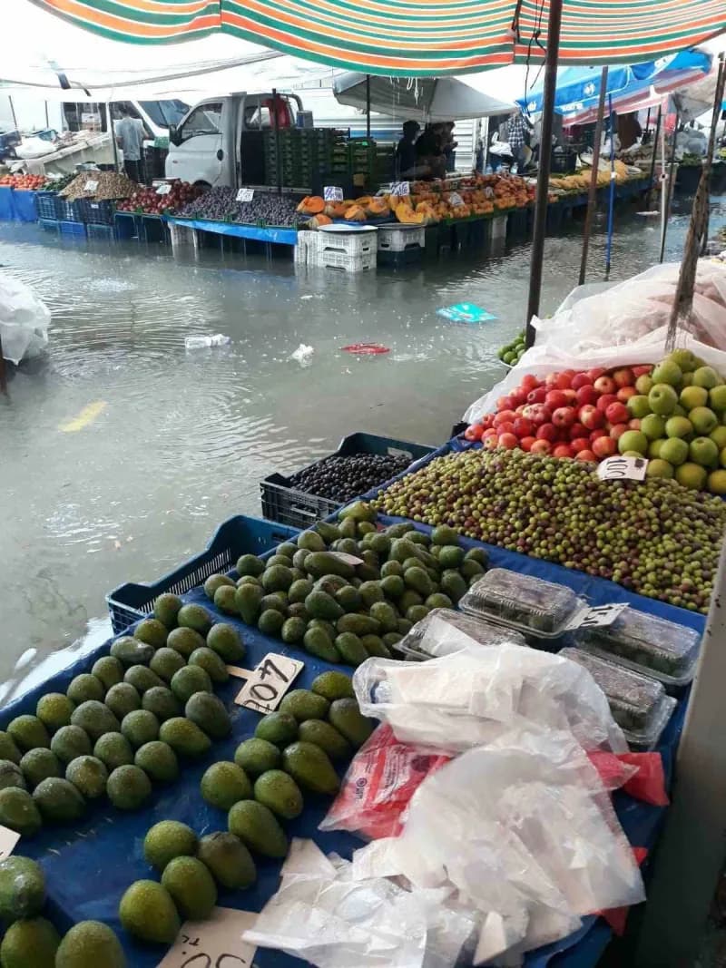 Tezgahlarını sabahın erken saatlerinde kuran pazarcı esnafı, ürünlerini ve tezgahlarını sudan korumaya çalışırken, bazı
