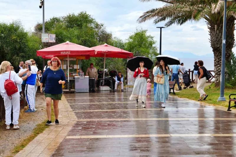 Şemsiyeleriyle gezen turistler, yeşillikler arasından Akdeniz'e uzanan şelaleyi fotoğraflayıp özçekim yaparken, botlarla