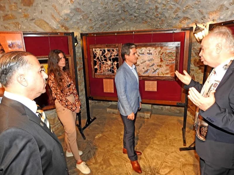 Ali Rıza İşipek (Sağda), Çeşme Kaymakamı Mehmet Maraşlı'ya (Ortada) sergisi hakkında bilgi verdi