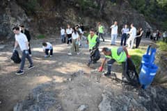 Kemer Çalış Tepesi’nde düzenlenen çevre temizliği etkinliğinde katılımcılar atıkları topluyor