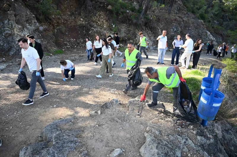 Kemer Çalış Tepesi’nde düzenlenen çevre temizliği etkinliğinde katılımcılar atıkları topluyor
