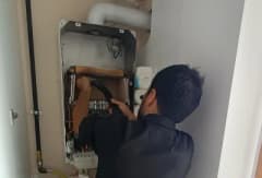 Kombi bakım işlemi yapan teknisyen kombi cihazı üzerinde kontrol yapıyor