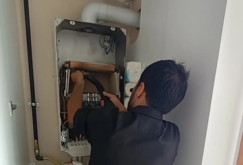 Kombi bakım işlemi yapan teknisyen kombi cihazı üzerinde kontrol yapıyor