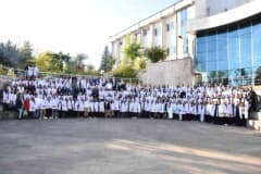 Düzce Üniversitesi Eğitim Fakültesi'nde öğretmen adayları önlüklerini giyerken tören alanında toplu fotoğraf