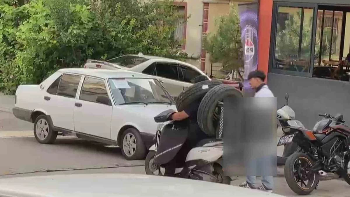 Ankara Kahramankazan'da motosikletli kurye otomobil lastiğini boynuna asarak taşıyor